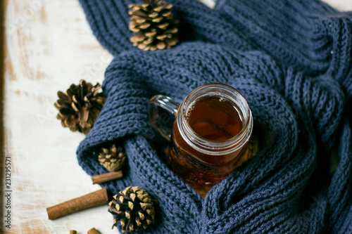 Autumn still life. cup of tea, Scarf and cinnamon sticks on wooden background.
