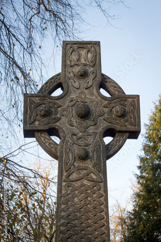 A celtic cross glowing  in the light of an Autumn sunset .