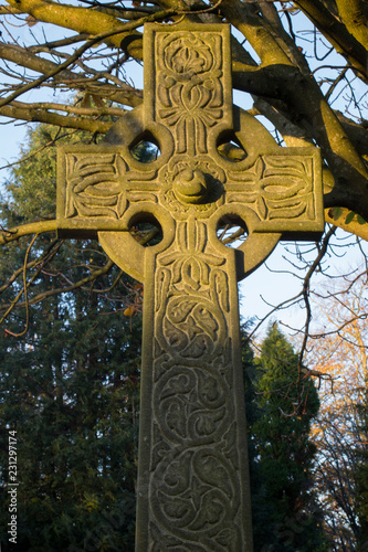 A celtic cross glowing  in the light of an Autumn sunset .