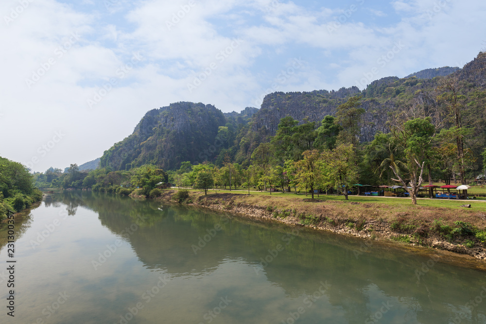 Nam Song River and limestone karst mountains near the Tham Chang (or Jang or Jung) Cave in Vang Vieng, Laos, on a sunny day.