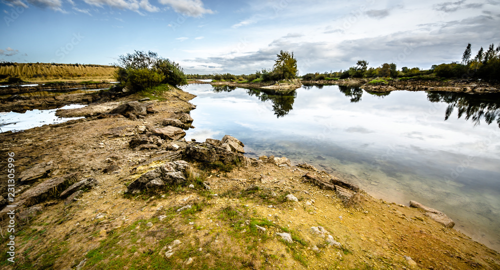 Sandy hills. Lake in the Sandy canyon. Warm colors background. Yellow sandstone textured mountain, white thin sand dune, bright sky. Sunshine landscape