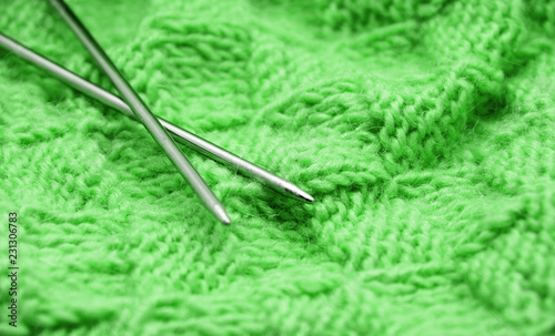 Detail of woven handicraft knit woolen design texture and knitting needle. Fabric green background © nata777_7