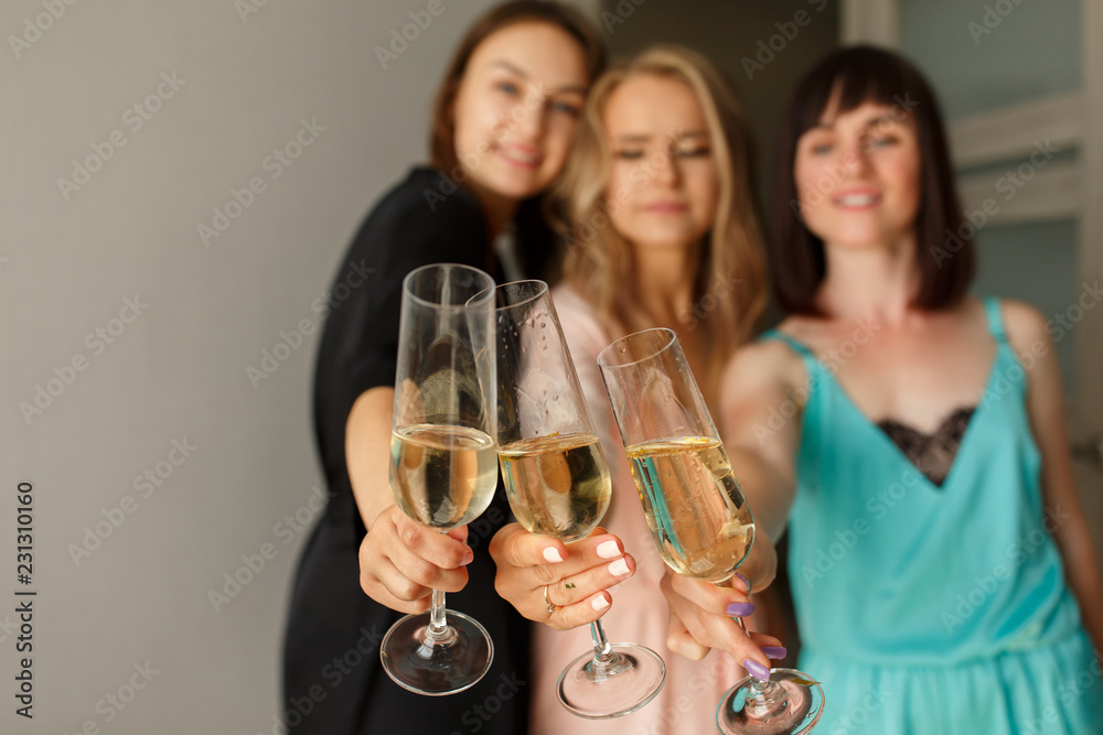 Women party. Three funny beautiful women with glasses of champagne posing at camera, having fun together at the bachelorette party. Dressed in silk pajamas. Hen party, happy birthday concept Women party. Three funny beautiful women with glasses of champagne posing at camera, having fun together at the bachelorette party. Dressed in silk pajamas. Hen party, happy birthday concept