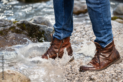 Wanderer mit braunen Schuhen an einem Bachlauf photo