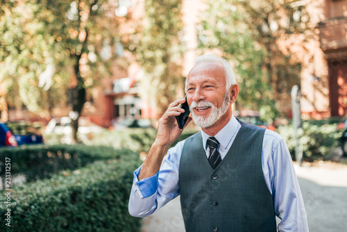 Charming older business man talking on the phone outdoors.