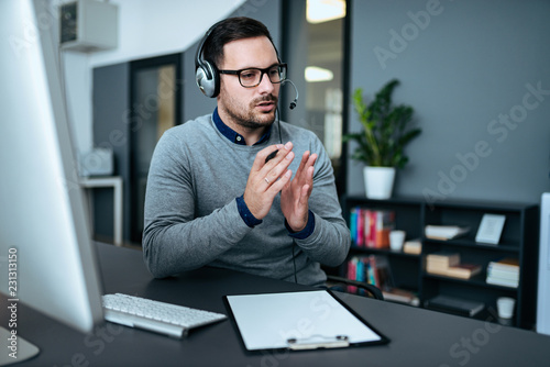 Young handsome male customer support phone operator with headset working in his office.