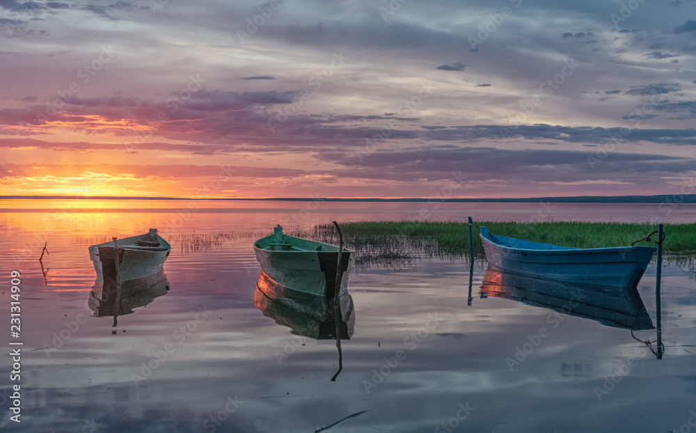 Φωτογραφία sunset rays reflected from wooden boats in the calm water of a lake Plesheevo in