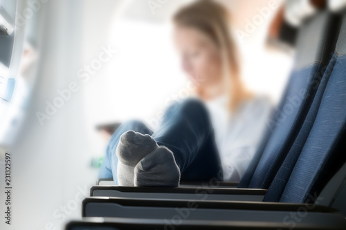 Young woman with legs on the plane seat. A passenger relaxes on a flying plane with her feet upstairs.