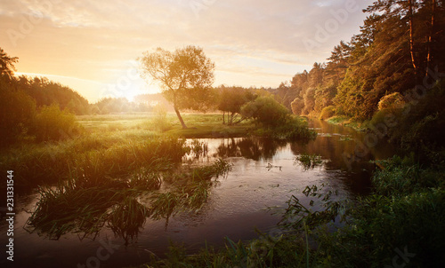 Sunset over the river in the forest. Beautiful bright dramatic sunset over river with forest along riverside.