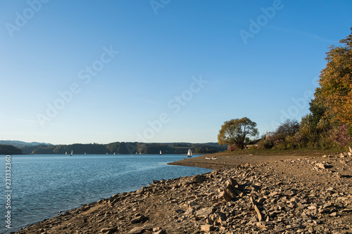 Autumn. Stone beach. Sailboats sailing on the lake.