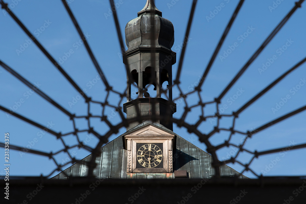 Hours with a bell tower behind a memorial fence.