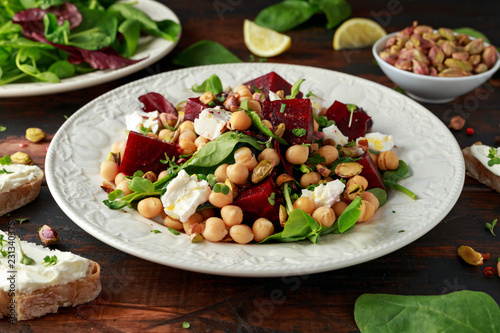 Healthy Beet Salad with chickpeas, pistachios nuts, feta and melted cheese toast on rustic wooden background