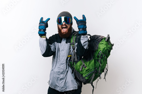 Portrait of amazed hiker man with hiking equipment for winter showing rock gesture and scraming