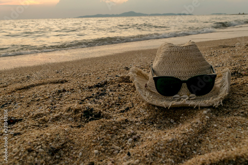 straw hat bespectacled sunglasses  on the beach during sunset © Suwincha