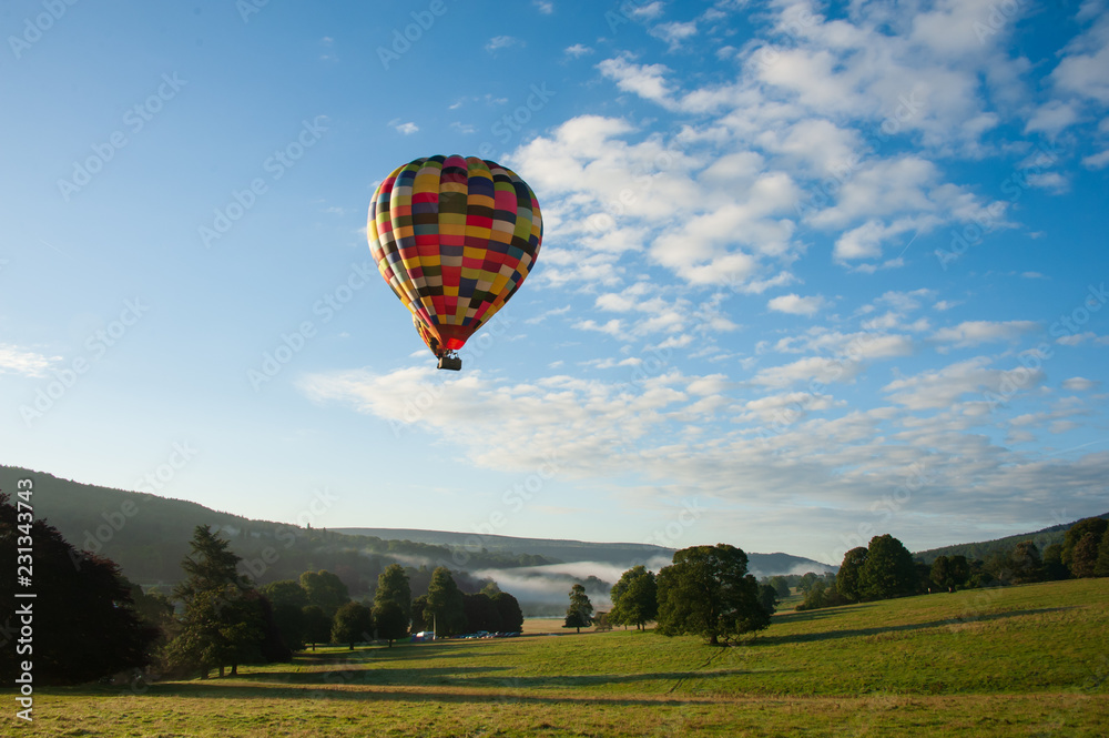 Fototapeta premium hot air balloon in the sky over misty hills