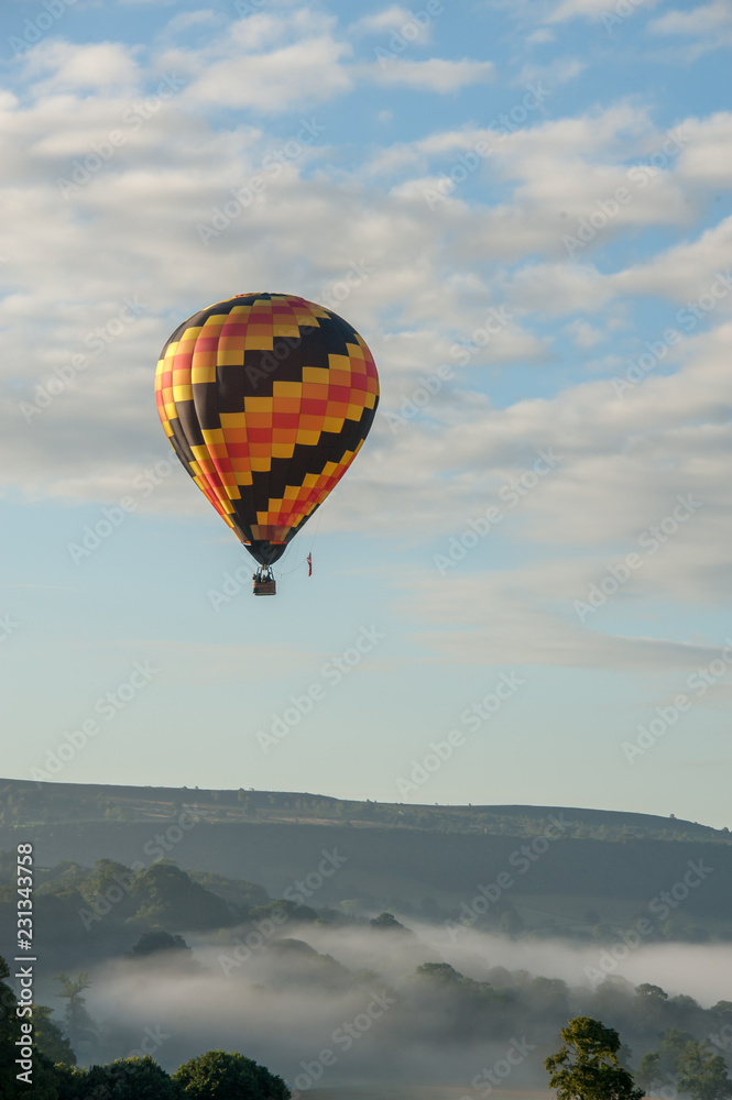 Obraz premium hot air balloon flying over english misty hills