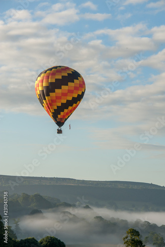 hot air balloon flying over english misty hills