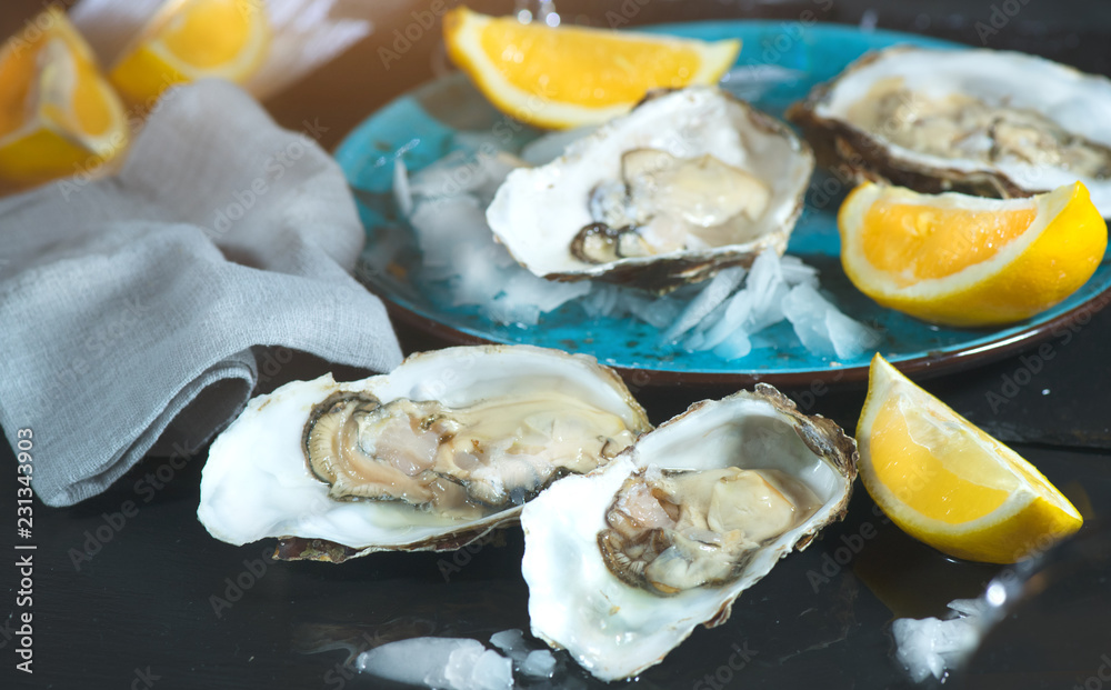 Fresh Oysters closeup on blue plate, served table with oysters, lemon and ice. Healthy sea food. Oyster dinner in restaurant. Gourmet food Fresh Oysters closeup on blue plate, served table with oysters, lemon and ice. Healthy sea food. Oyster dinner in restaurant. Gourmet food