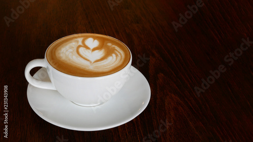 Hot coffee cappuccino latte art tulip foam in ceramic cup on dark wooden table background