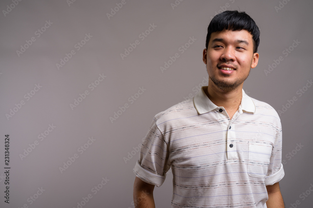 Portrait of young Asian man against gray background Portrait of young Asian man against gray background