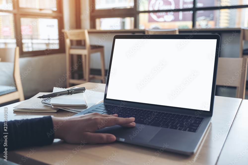 Mockup image of a hand using and touching laptop touchpad with blank white desktop screen while sitting in office Mockup image of a hand using and touching laptop touchpad with blank white desktop screen while sitting in office