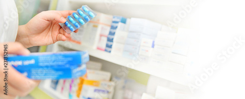 Pharmacist holding medicine box and capsule pack in pharmacy drugstore.copy space