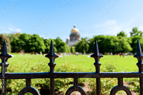 City Park with People Relaxing on Grass Field near Saint Isaac's Cathedral in St.Petersburg, Russia. Big Local Park with Green Lawn and Cathedral View on Sunny Summer Day with Empty Background.
