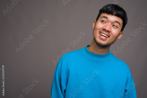 Portrait of young Asian man against gray background