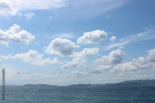 Distant shore landscape with sea, sky and puffy clouds