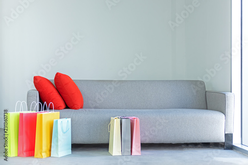 Shopping online. Colorful shopping bags with red pillow on sofa in the living room.