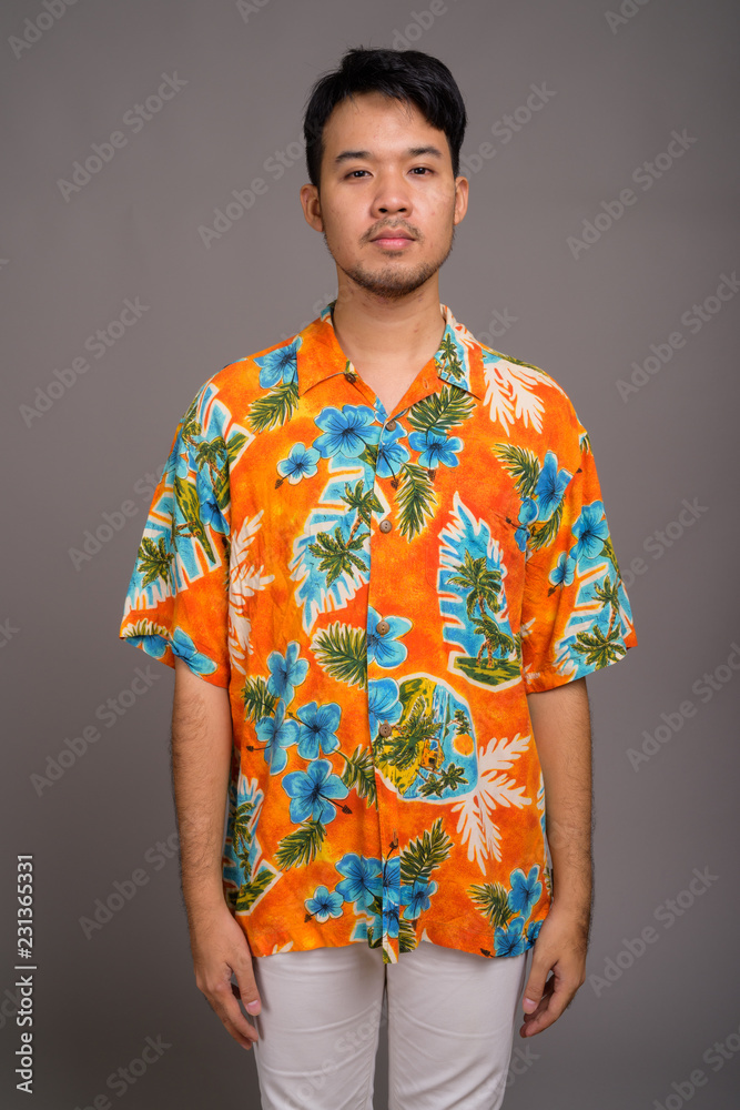 Young Asian tourist man ready for vacation against gray backgrou Young Asian tourist man ready for vacation against gray backgrou