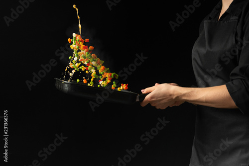 Fototapeta Naklejka Na Ścianę i Meble -  Flying mixed vegetables in a pan. Diet healthy food. Black background for copying text. Concept of food and cooking.