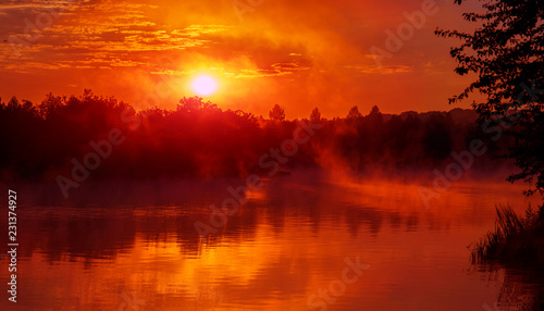 wonderful misty morning. majestic red sunrise over the foggy lake