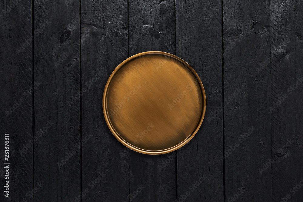 Top view of golden stylish serving plate on black wooden table with copy space. Top view of golden stylish serving plate on black wooden table with copy space.