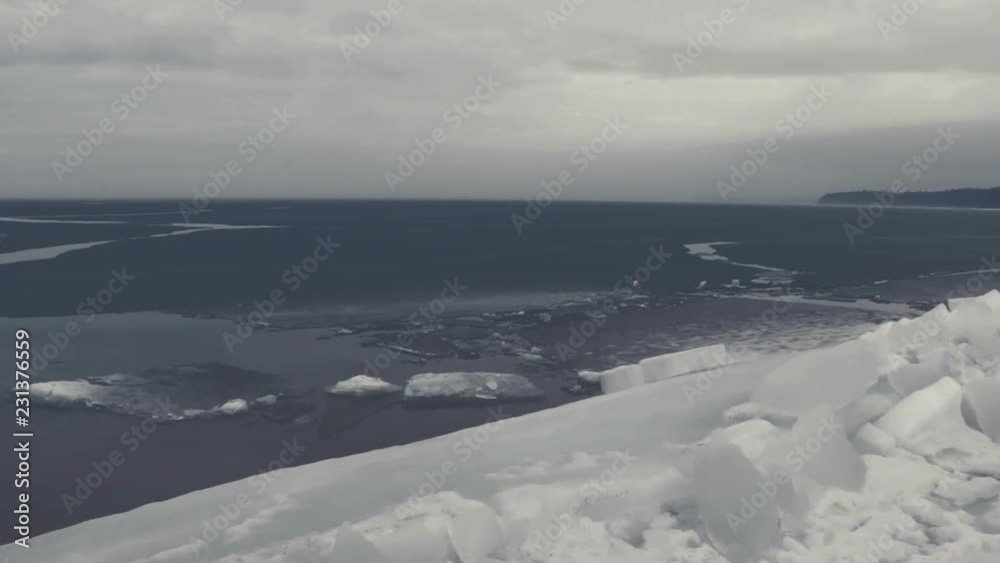 Foggy bluish sea coast line in spring during ice breaking. Slow pan of shore, frozen beach, ice and open water. Foggy bluish sea coast line in spring during ice breaking. Slow pan of shore, frozen beach, ice and open water.