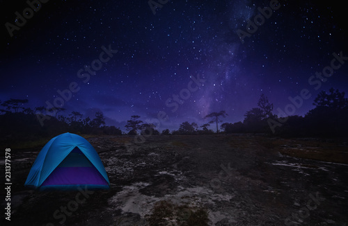Illuminated Blue Camping Tents of Travel Camper in Starry Night with Milky Way on the Peaceful Rock Mountain - Outdoor Activity in Summer