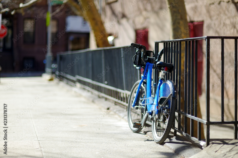 Rental bicycles left by a fence in New York City.