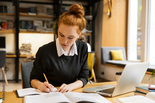 Pretty red haired teenage girl using laptop computer