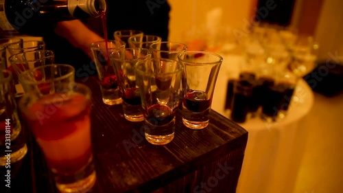 Barman pours alcoholic beverages. Dark room, poor lighting