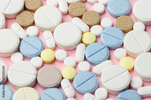 multi-colored tablets of different shapes close-up on a pink background