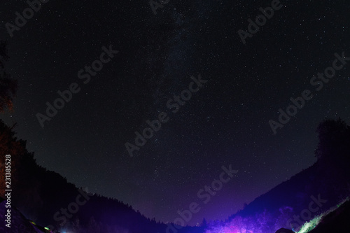 Night starry sky above the forest in the mountains