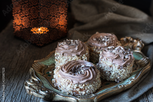 Biscuit cakes  sprinkled with nut chips and decorated with chocolate cream  are next to the candlestick with a dying candle in the background and illuminated by the morning  light from the window