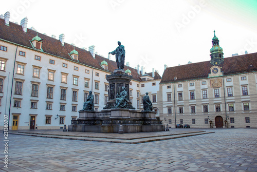 Town square in Vienna Austria with a large monument containing four statues.
