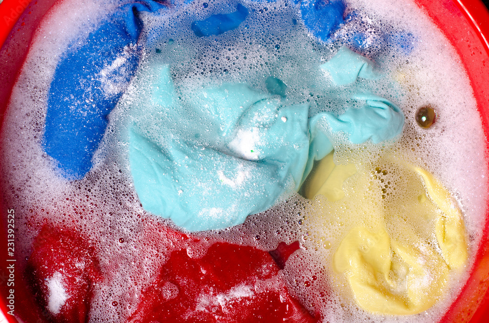 Fototapeta premium Washing color clothes in basin enemale powdered detergent, top view