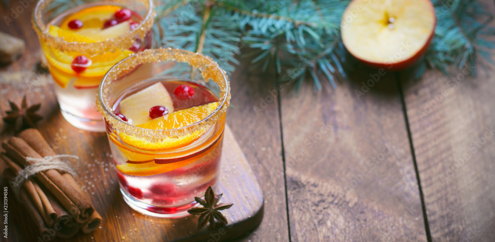 Fototapeta premium Winter Cocktail, Christmas Sangria with Apple Slices, Orange, Cranberry and Spices, Refreshing Drink on Wooden Background