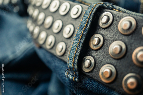 close up detail of an unbuckled leather belt on a faded pair of blue jeans photo