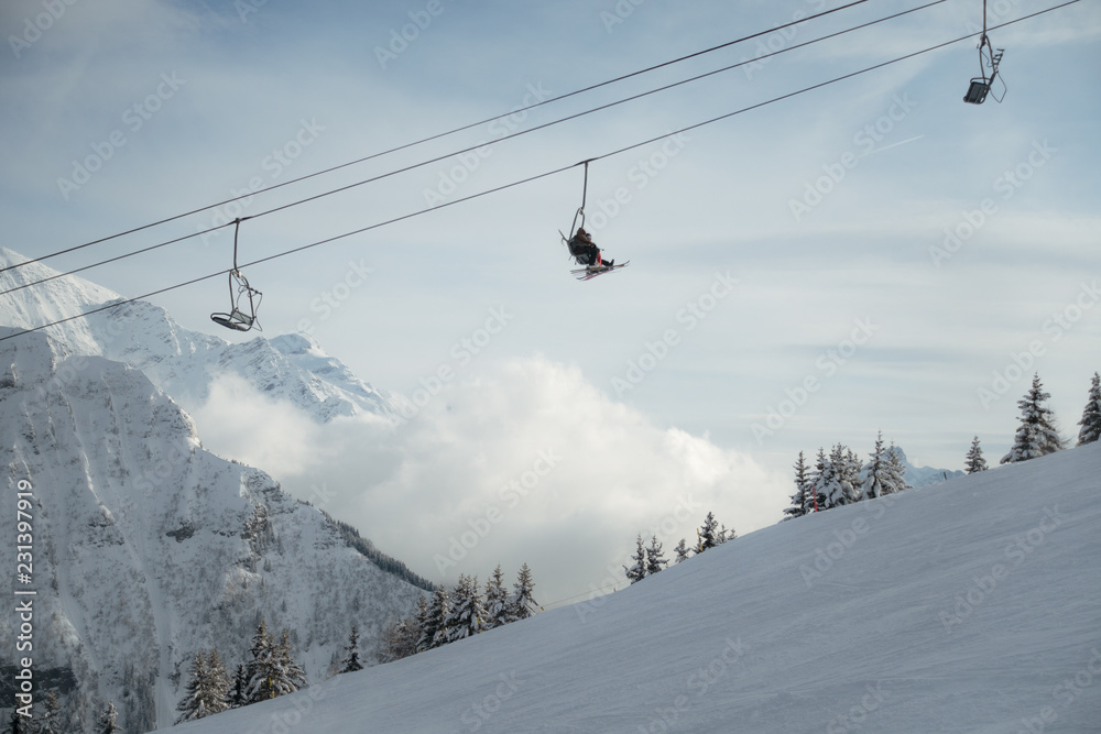 Skiers in ski lift high in snowy cloudy mountain