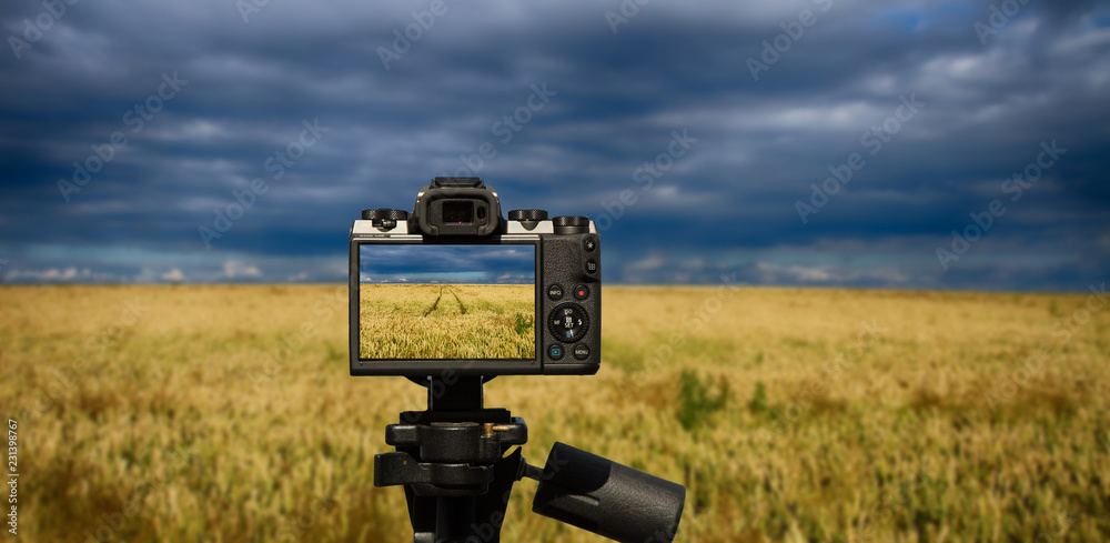 camera and Dark, stormy sky and a field of ripening cereal