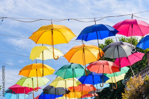 Different colorful umbrellas hanging over the street against sky