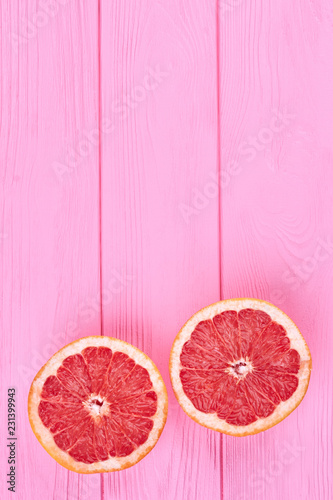 Two halves of grapefruit, top view. Flat lay cutted grapefruit on two halves on pink wooden backgrorund with copy space. Health and beauty.